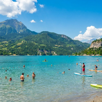 Vue panoramique du Plan d'Eau d'Embrun avec la ville fortifiée sur la falaise et le lac de Serre-Ponçon, idéal pour la baignade